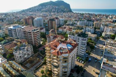 Alanya Immobilie Wohnzimmer mit hellgrünen Sofas, offener Küche und natürlichem Licht, das eine einladende Atmosphäre schafft.