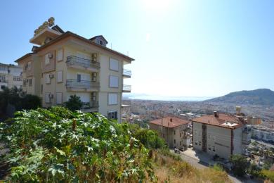 Alānijas īpašuma balkons ar flīžu grīdu, greznām dzelzs margām un panorāmas skatu uz pilsētu un piekrasti.