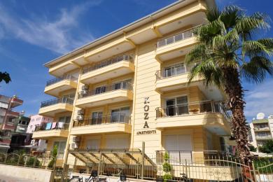 Lys stue i Alanya med en hvit seksjonssofa, spiseområde og nøytral innredning, som skaper en rolig atmosfære.