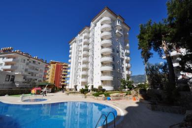 Alanya ejendom altan med flisegulv, rustfrit stål rækværk og strålende solskin med udsigt over byen og havet.