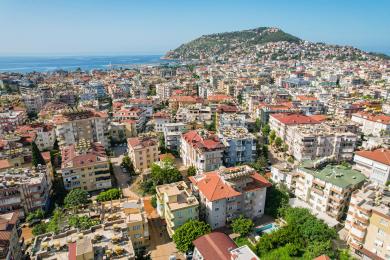 Alanya altan med bord, stole og solrig udsigt over de omkringliggende bygninger.