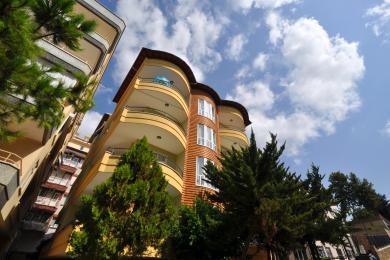 Μπαλκόνι ακινήτου στην Αλάνια με ψάθινες καρέκλες, τραπέζι και σιδερένια κουπαστή που προσφέρει θέα στην πόλη.