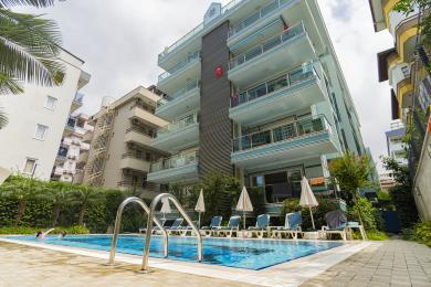 تراس پشت بام ملک آلانیا دارای جکوزی چوبی و منظره پانوراما از شهر زیر نور روشن روز است.
