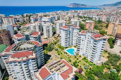Alanya fastighet balkong med bergsutsikt, med rottingstolar och marmorräcken i starkt, naturligt ljus.