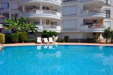 Слънчевата тераса на покрива на имот в Алания разполага с каменна настилка, мивка и панорамна гледка към града и планината.