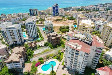 Alanya ejendom altan med kurvestole, stenbord og lyse, solrige udsigter over nærliggende bygninger.