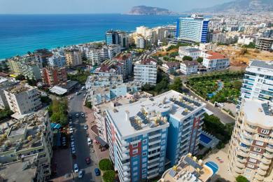 Alanya ingatlan nappalija márványpadlóval, fehér bőrkanapékkal és világos, szellős erkéllyel.