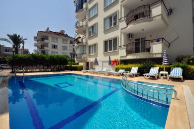 Alanya kinnisvara elutuba kreemika diivani, tugitoolide, klaaslaua ja pehme loomuliku valgusega.