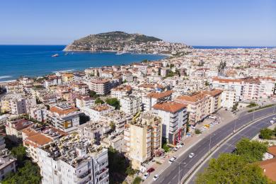 Alanya eiendom balkong med kurvmøbler tilbyr fantastisk utsikt over byen og havet under sterkt, naturlig lys.