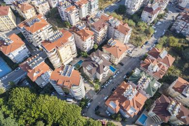 Etageejendom med balkoner og skodder, beliggende i et solrigt, træbeklædt kvarter.