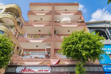 Alānijas īpašuma balkons ar pītu ēdamistabas komplektu, flīžu grīdu un panorāmas skatu uz pilsētu un kalniem.