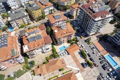 Solig balkong i Alanya med vitt bord och stolar, med utsikt över staden.