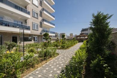 De lichte keuken van dit appartement in Alanya is voorzien van witte kasten, zwarte werkbladen, een betegelde achterwand met patroon en glanzende tegelvloeren.