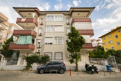 Svetlý apartmán v Alanyi ponúka kuchyňu s otvoreným priestorom s bielymi skrinkami, dlažbou a pohodlnou obývacou časťou.