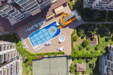 Lichte, open Alanya woonkamer met tegelvloeren, moderne meubels en natuurlijk licht dat een ruimtelijke sfeer creëert.
