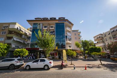 Alanya eiendom stue med beige sofa, flislagte gulv, balkongtilgang og moderne belysning.