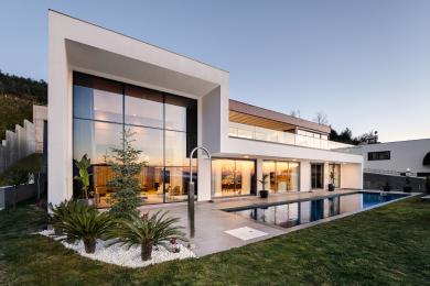 Helle, moderne Alanya Küche mit weißen Schränken, Marmorarbeitsplatten, Sitzinsel und transparenten Fensterabdeckungen.