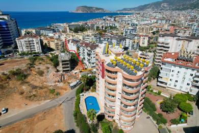 Alanya-Immobilie mit offenem Wohnbereich mit Küche, Esstisch und bequemem Sofa, alles beleuchtet von warmem, natürlichem Licht.