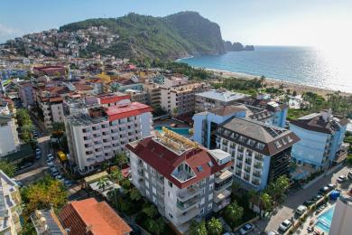 Alanya eign stofa með flísalögðum gólfum, hlutlausum tónum, þægilegum sætum og björtu náttúrulegu ljósi sem sýnir útsýni til fjalla.