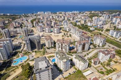 Solrik Alanya-balkong med utsikt over bassenget, med et spisested og en lys og luftig atmosfære.