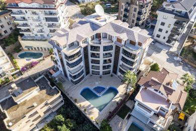 Nieruchomość w Alanyi: Zamknięty balkon ze szklanymi ścianami, meblami z wikliny i jasną, przestronną atmosferą z widokiem na miasto.
