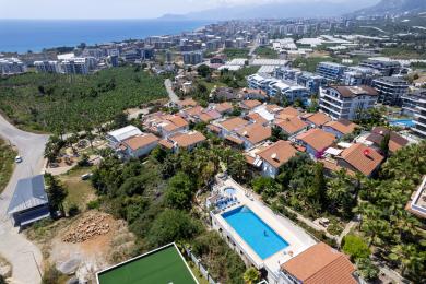 Balkon nekretnine u Alanji s drvenim krovom, bijelim namještajem i prekrasnim pogledom na more, stvarajući opuštajuću atmosferu.
