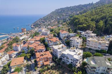 Alanya stofa með terracotta sófa, glersborði og svölum með sjávarútsýni, sem skapar bjarta og loftgóða stemningu.