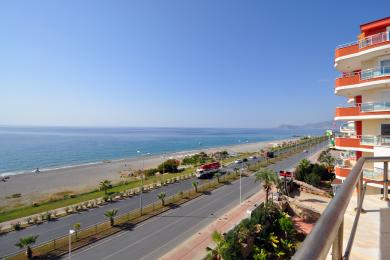 Alanya ejendom balkonudsigt, der viser stranden, kystlinjen og den lyse, solrige atmosfære.