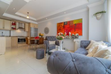 Der offene Wohnbereich dieser Immobilie in Alanya verfügt über eine moderne Küche, ein Esszimmer-Set und luxuriöse blaue Samtsitze.