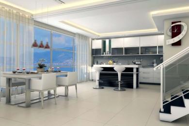 Alanya property featuring a bright, modern kitchen and dining area with sea views, white cabinetry, and a sleek, minimalist design.