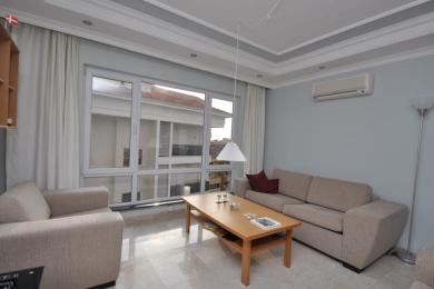 Dnevna soba u Alanyi s neutralnim sofama, mramornim podovima i jakom prirodnom svjetlošću koja dolazi kroz velike prozore.