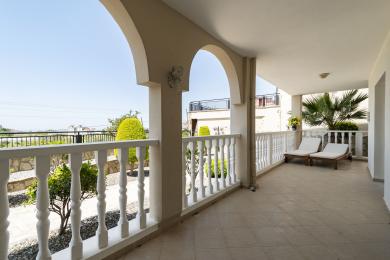 Alanya ejendom altan med buede åbninger, hvide rækværk, flisegulv og solrig udsigt til haven.