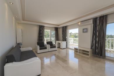 Bright Alanya living room with marble floors, grey sofa, balcony access, and neutral decor creates a serene atmosphere.
