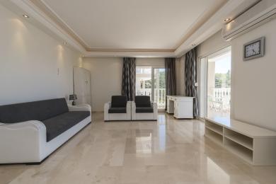 Яркая гасцёўня ў Аланьі з мармуровай падлогай, канапай, крэсламі і выхадам на балкон, ствараючы прасторнае, светлае адчуванне.
