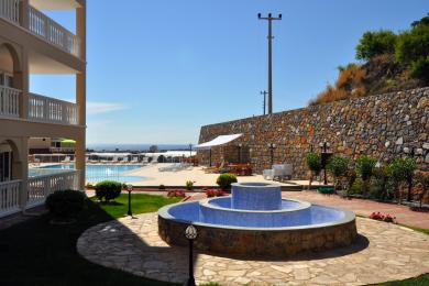 Alanya ejendom har et smukt udendørs poolområde med en flisebelagt fontæne og stenvæg, der skaber en afslappende atmosfære.