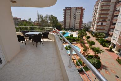 Alanya ejendom balkon med flisegulv, kurvemøbler og udsigt over poolen og de anlagte områder.