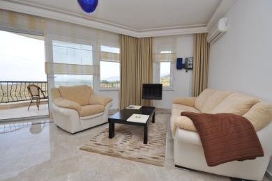 Alanya living room with balcony access, featuring neutral tones, marble floors, and comfortable seating, creating a bright, airy atmosphere.