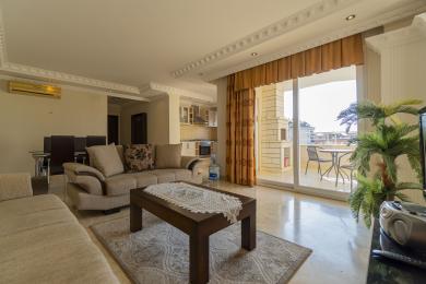 Living spațios și luminos în Alanya, cu podele de marmură, canapele confortabile și acces la balcon cu vedere spre oraș.
