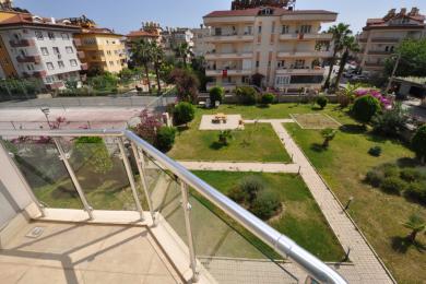 Alanya ejendom balkon med glasrækværk tilbyder en lys udsigt over den anlagte have.