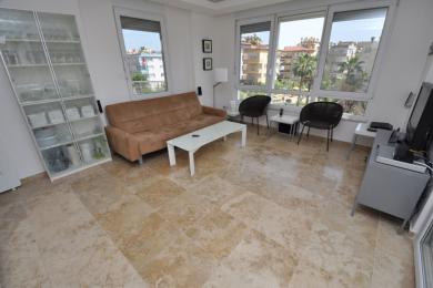 Lys stue i Alanya med travertingulve, sofa og store vinduer med udsigt over byen.