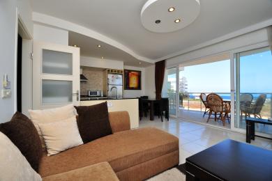 Alanya Apartment Wohnzimmer mit offener Küche, Zugang zum Balkon, Fliesenböden und heller, luftiger Atmosphäre.