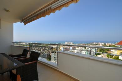 Alanya ejendom balkon med kurvemøbler og fantastisk panoramaudsigt over havet og byen.