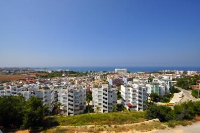 Alanya ejendomsvisning, der viser byens skyline og Middelhavet under en klar blå himmel.