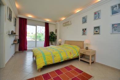 Een heldere Alanya slaapkamer met toegang tot het balkon, voorzien van tegelvloeren, een gele sprei en warme, uitnodigende verlichting.