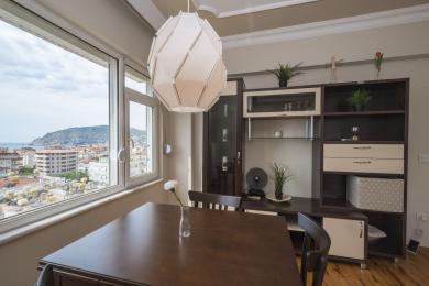 Jadalnia w Alanyi z drewnianym stołem, nowoczesnym oświetleniem i jasnym widokiem z okna.