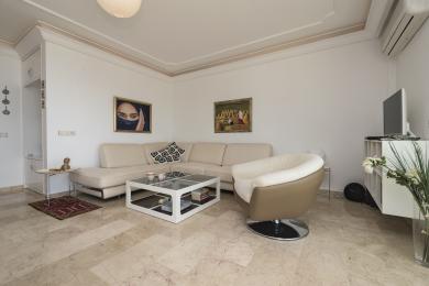 Bright Alanya living room with marble floors, cream sofa, modern armchair, and decorative artwork creating a comfortable atmosphere.