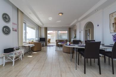 Heller Wohn- und Essbereich in einem Apartment in Alanya mit Fliesenböden, Zugang zum Balkon und moderner Einrichtung.