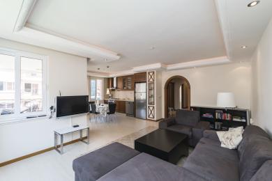 Аланійська нерухомість: вітальня відкритого плану з кухнею, з кахельною підлогою, вбудованим освітленням і зручними сірими сидіннями.