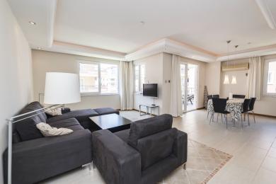Helles Alanya Apartment Wohnzimmer mit dunklem Sofa, Fliesenböden, Essbereich und Zugang zum Balkon.