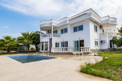 Alanya villa eksteriør med privat basseng, hvit fasade, balkonger og solrik middelhavsatmosfære.